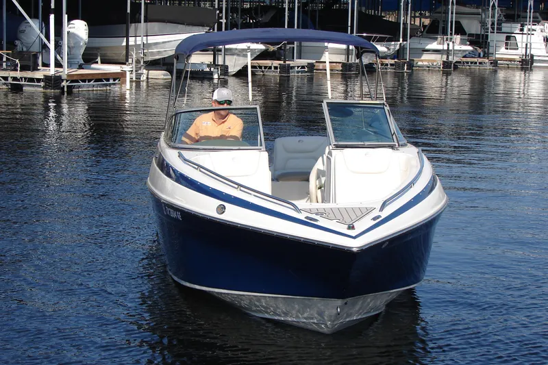 Slide: The Image of 2008 Crownline 270 BR boat on water, with a person at the helm, docked in a marina. - 8
