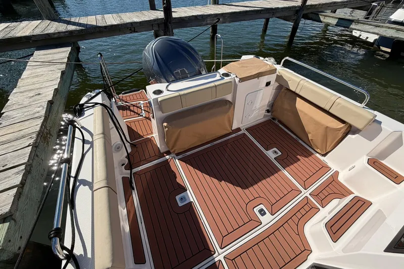 Slide: The Image of 2023 Ranger Tugs R-25 boat deck with wood finish and seating at dock. - 20