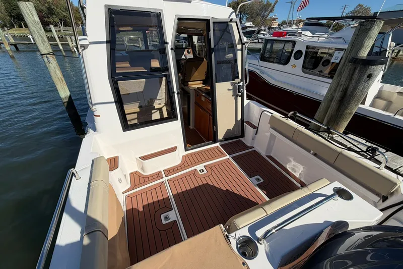 Slide: The Image of 2023 Ranger Tugs R-25 boat with open cabin door, docked at marina. - 21