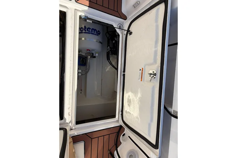 Slide: The Image of 2023 Ranger Tugs R-25 storage compartment with water heater and wiring. - 26