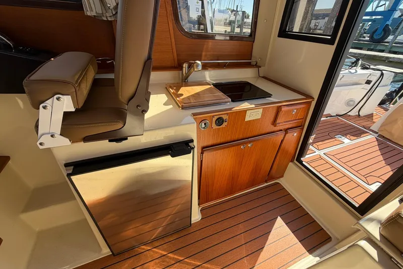 Slide: The Image of 2023 Ranger Tugs R-25 interior with kitchenette, wooden cabinetry, and seating. - 33