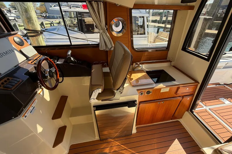 Slide: The Image of 2023 Ranger Tugs R-25 interior with helm, kitchenette, and wood accents. - 34
