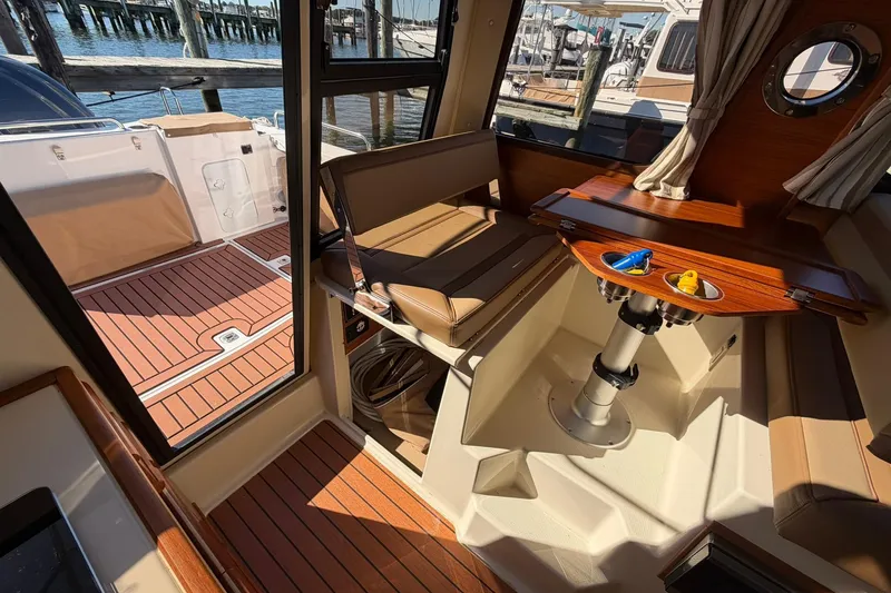 Slide: The Image of 2023 Ranger Tugs R-25 interior with wood accents and seating, docked by the water. - 36