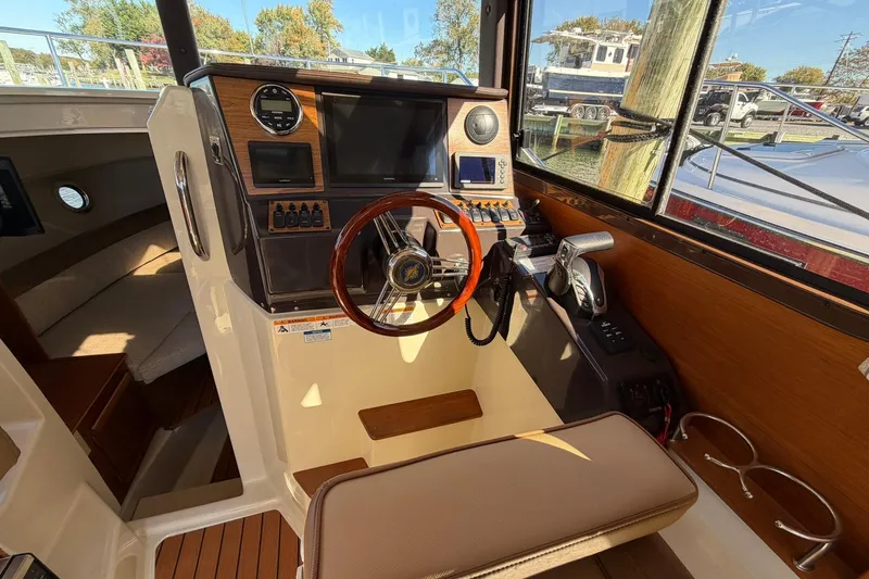 Slide: The Image of 2023 Ranger Tugs R-25 helm with wooden steering wheel and modern navigation controls. - 41