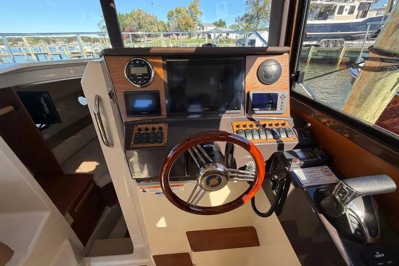 Slide: The Image of 2023 Ranger Tugs R-25 helm with modern navigation controls and wooden steering wheel. - 42