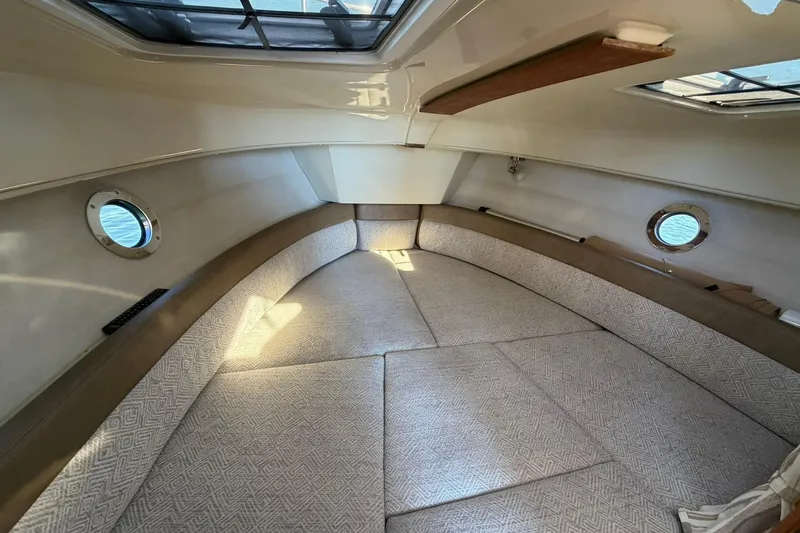 Slide: The Image of 2023 Ranger Tugs R-25 cabin interior with cozy seating and porthole windows. - 47