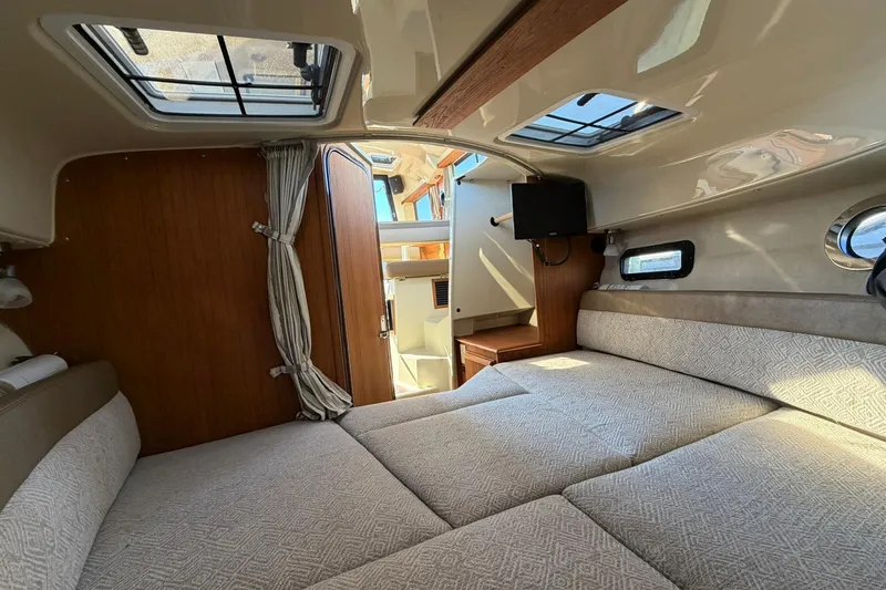 Slide: The Image of 2023 Ranger Tugs R-25 interior cabin with bed, skylights, and wooden accents. - 48