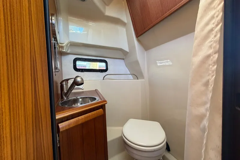 Slide: The Image of 2023 Ranger Tugs R-25 boat bathroom with sink, toilet, and wooden cabinetry. - 52