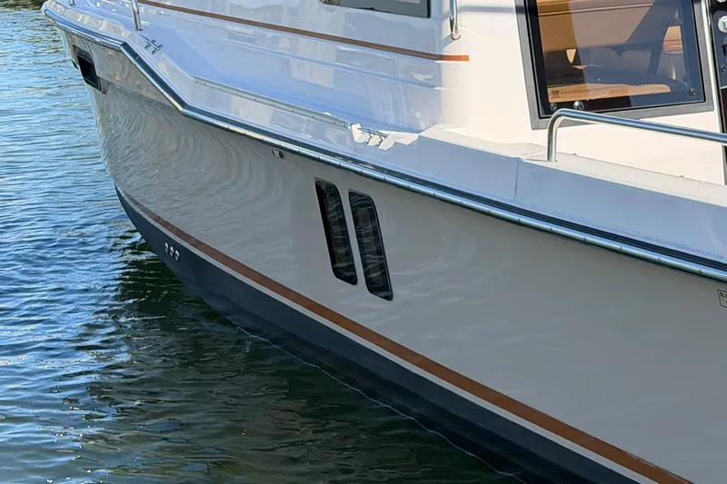 Slide: The Image of 2023 Ranger Tugs R-25 boat side view on water, showcasing sleek design. - 7