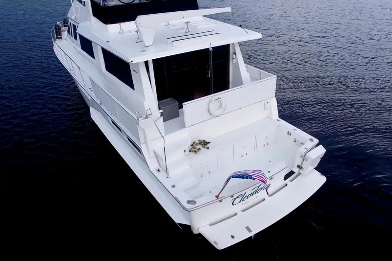 Slide: The Image of 1988 Viking 63 Cockpit Motor Yacht on calm water, rear view with American flag. - 11