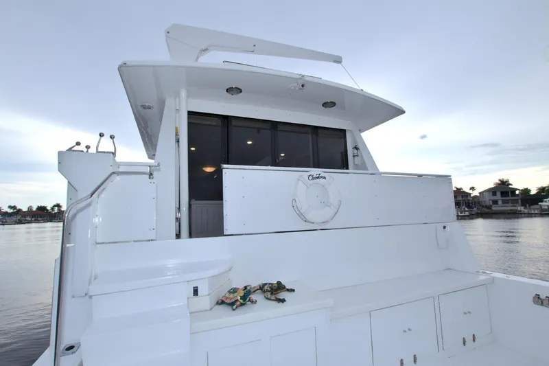 Slide: The Image of 1988 Viking 63 Cockpit Motor Yacht stern view with spacious deck and water backdrop. - 14