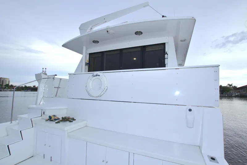 Slide: The Image of 1988 Viking 63 Cockpit Motor Yacht rear view with white exterior and water backdrop. - 15