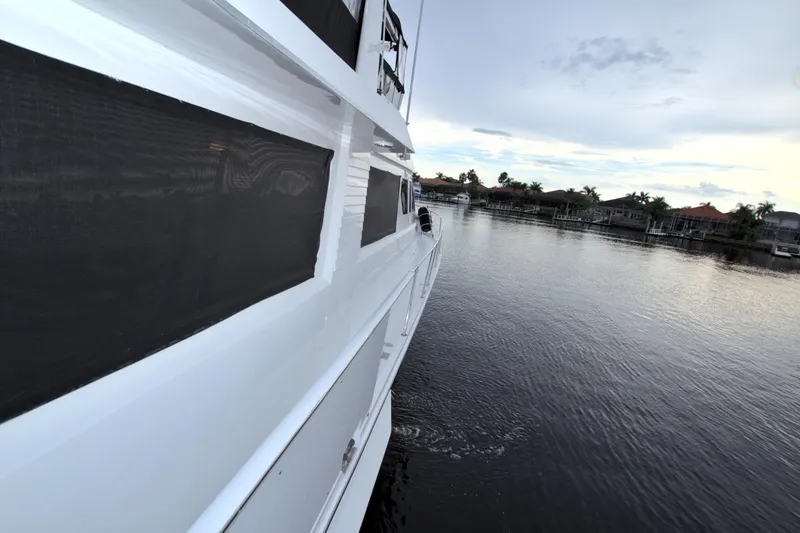 Slide: The Image of Side view of 1988 Viking 63 Cockpit Motor Yacht on calm water. - 20