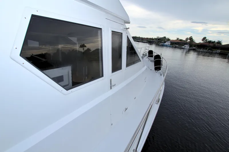 Slide: The Image of Side view of 1988 Viking 63 Cockpit Motor Yacht on calm water. - 22