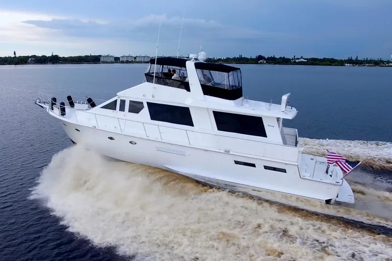 Slide: The Image of 1988 Viking 63 Cockpit Motor Yacht cruising on open water, American flag displayed. - 4