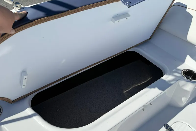 Slide: The Image of 2026 Stingray 182 SC boat storage compartment with open lid and cup holder. - 14