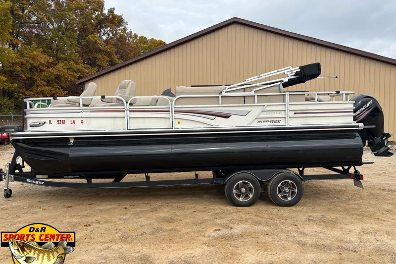 Slide: The Image of 2021 Ranger 223FC pontoon boat on trailer, parked outdoors near a building. - 1