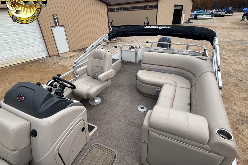 Slide: The Image of 2021 Ranger 223FC pontoon boat with beige seating and steering console, parked outdoors. - 4