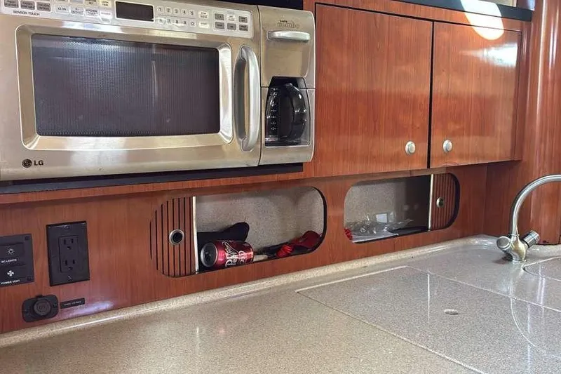 Slide: The Image of 2006 Sea Ray 340 Sundancer kitchen with microwave, wooden cabinets, and countertop. - 13