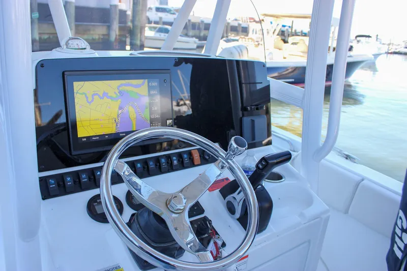 Slide: The Image of 2020 Sea Hunt Ultra 234 boat cruising on calm water with sailboats in the background. - 3