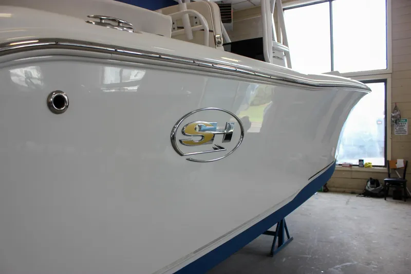 Slide: The Image of 2020 Sea Hunt Ultra 234 boat in showroom, featuring sleek white hull and logo. - 54