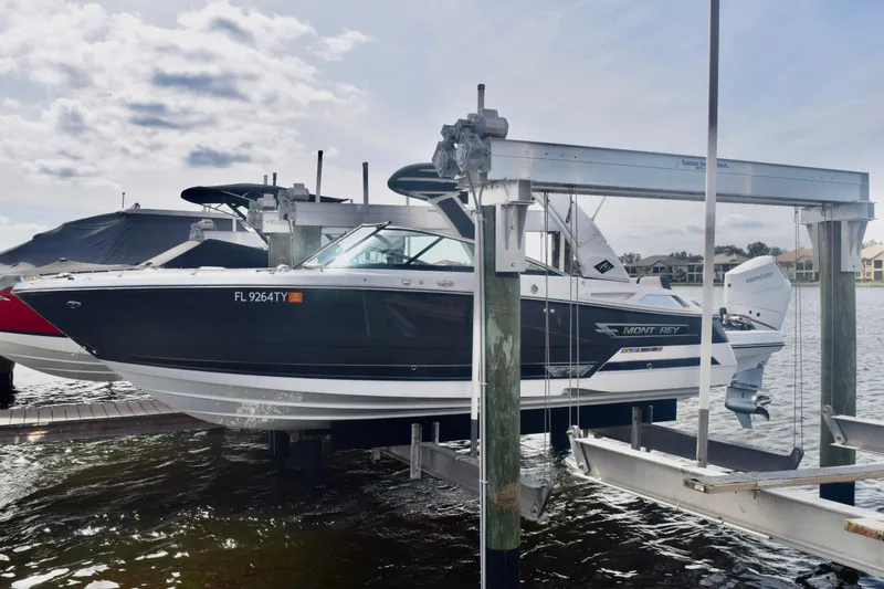 Slide: The Image of 2025 Monterey 275SS Super Sport boat on lift, docked by waterfront homes. - 3