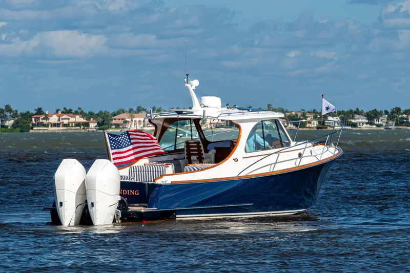 Slide: The Image of 2024 Hinckley 35 boat cruising on water with American flag, coastal homes in background. - 10