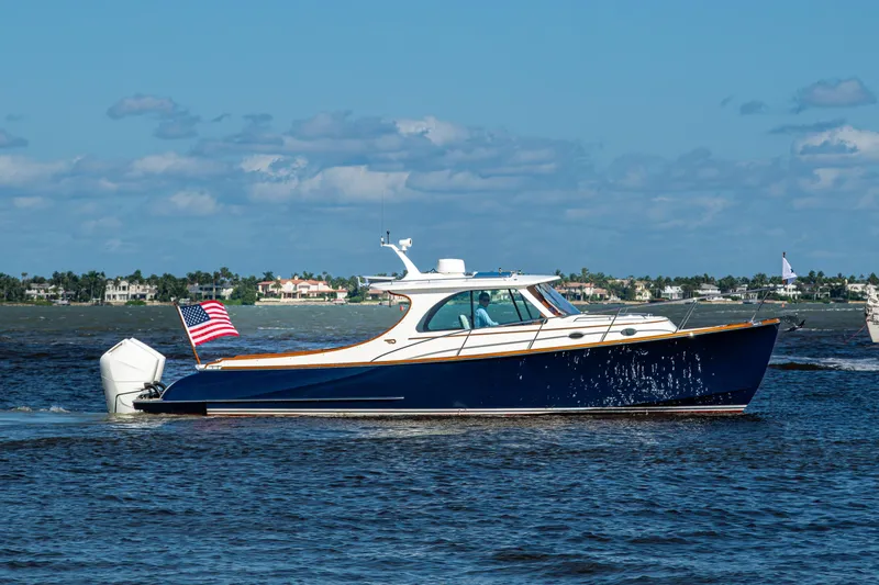 Slide: The Image of 2024 Hinckley 35 yacht cruising on water with American flag, clear sky background. - 12