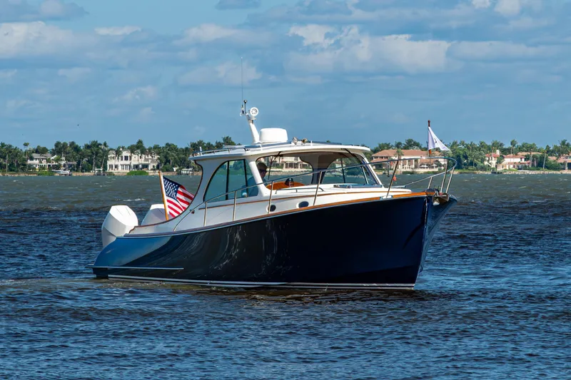 Slide: The Image of 2024 Hinckley 35 boat cruising on a sunny day with coastal homes in the background. - 15