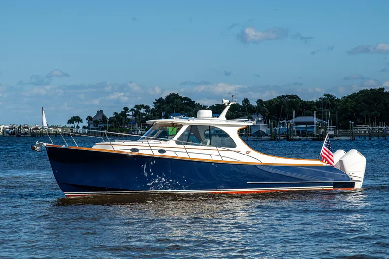 Slide: The Image of 2024 Hinckley 35 yacht on water, blue hull, American flag, sunny day. - 17