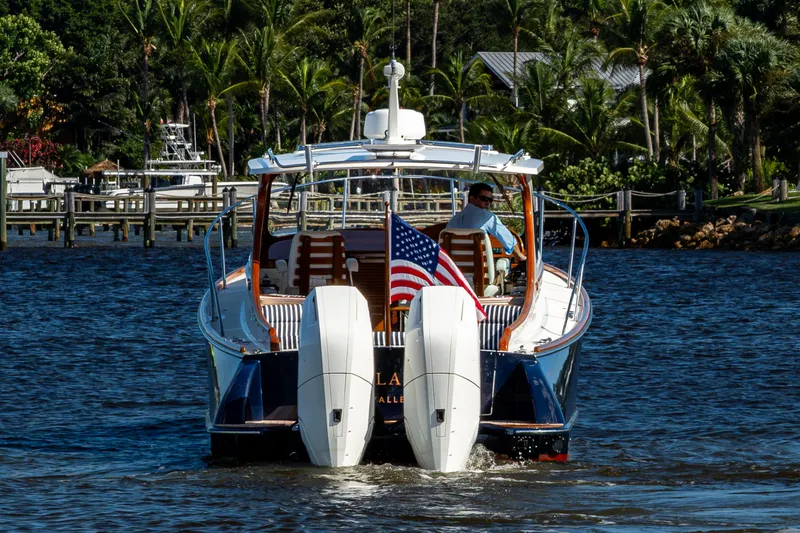 Slide: The Image of 2024 Hinckley 35 boat cruising on water, American flag displayed, lush greenery in background. - 21