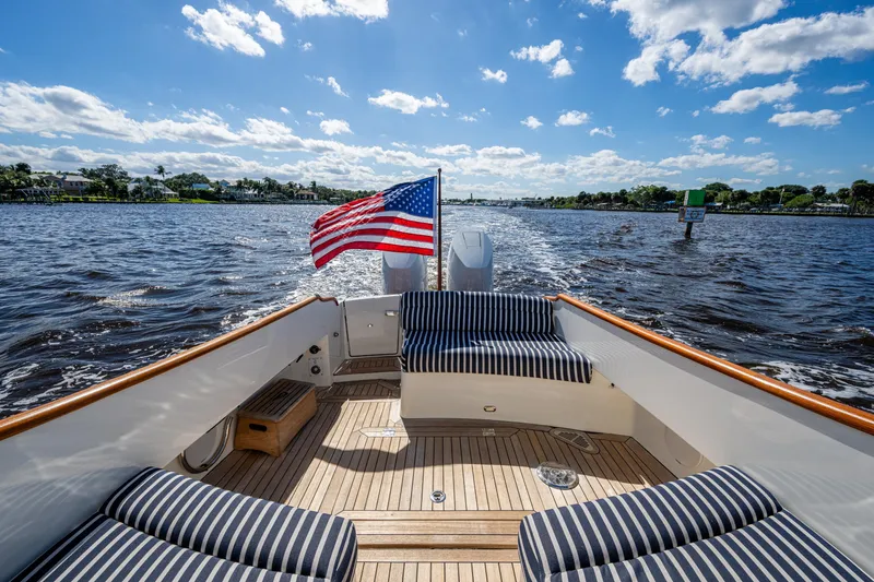 Slide: The Image of 2024 Hinckley 35 boat with striped seating, American flag, cruising on a sunny day. - 3