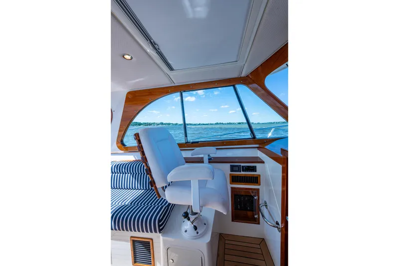 Slide: The Image of 2024 Hinckley 35 boat interior with captain's chair and scenic ocean view. - 37