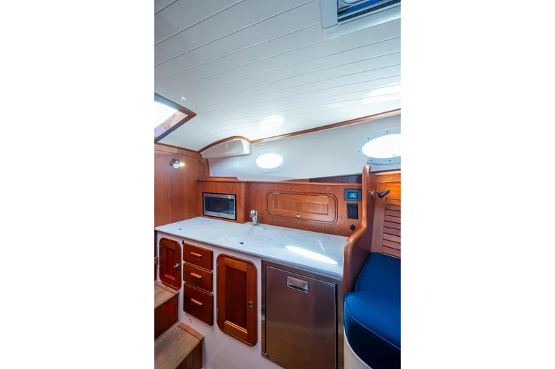 Slide: The Image of 2024 Hinckley 35 yacht interior with wooden cabinetry and modern appliances. - 46