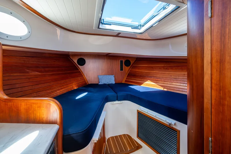 Slide: The Image of 2024 Hinckley 35 cabin interior with wooden finish and blue cushions. - 5