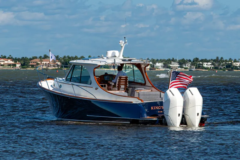 Slide: The Image of 2024 Hinckley 35 boat cruising on water with American flag, scenic coastal background. - 6