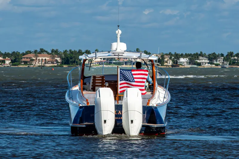 Slide: The Image of 2024 Hinckley 35 boat cruising with American flag, coastal homes in background. - 8