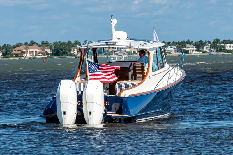 Slide: The Image of 2024 Hinckley 35 boat cruising on water with American flag, sunny day. - 9