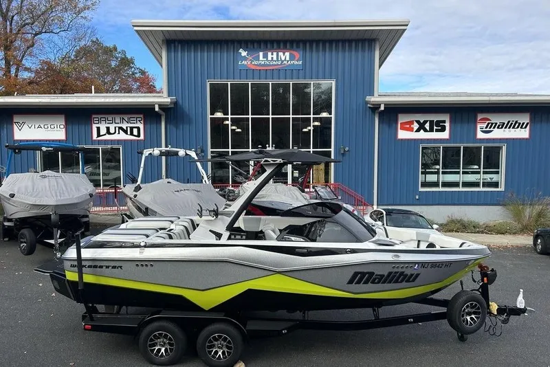 Slide: The Image of 2024 Malibu Wakesetter 22 LSV boat parked outside dealership, blue building background. - 4
