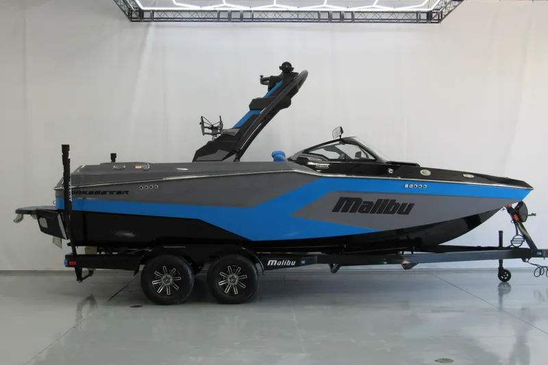 The Image of 2026 Malibu Wakesetter 22 MXZ boat in showroom, blue and gray design, on trailer. - 0