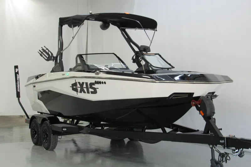 Slide: The Image of 2026 Axis A200 boat on trailer, sleek black and white design, in showroom setting. - 1