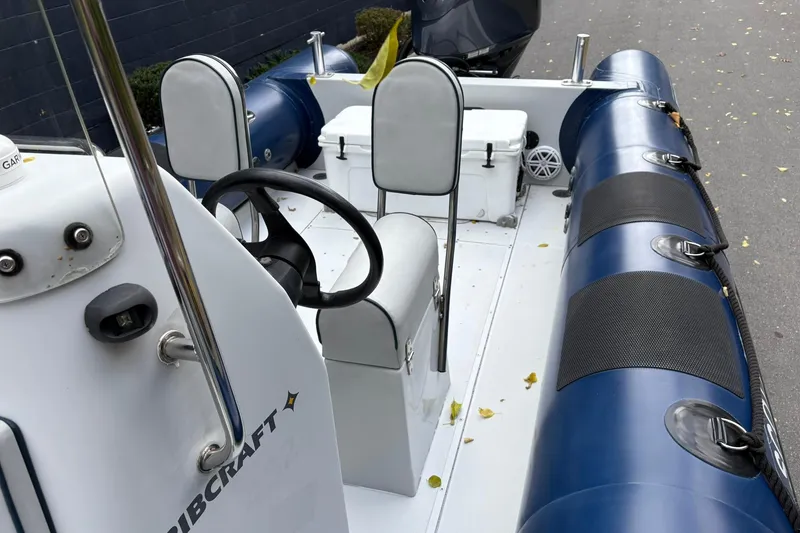 Slide: The Image of 2019 Ribcraft 7.8 boat interior with steering wheel and seating, featuring blue and white design. - 13