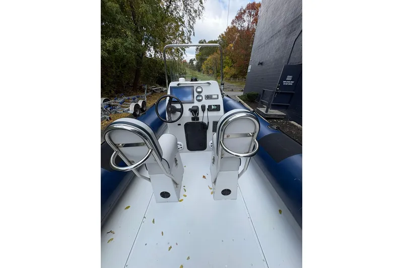 Slide: The Image of 2019 Ribcraft 7.8 boat interior with steering console and seating, surrounded by autumn foliage. - 15