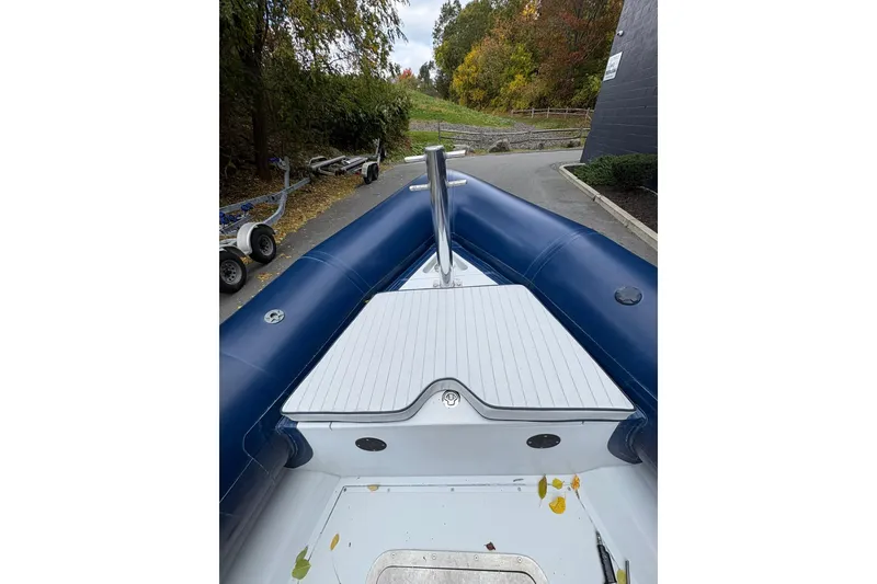 Slide: The Image of 2019 Ribcraft 7.8 inflatable boat, blue and white, docked near a wooded area. - 17