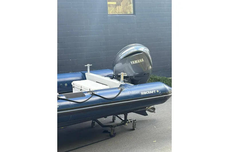 Slide: The Image of 2019 Ribcraft 7.8 inflatable boat with Yamaha outboard motor, parked on a trailer. - 2