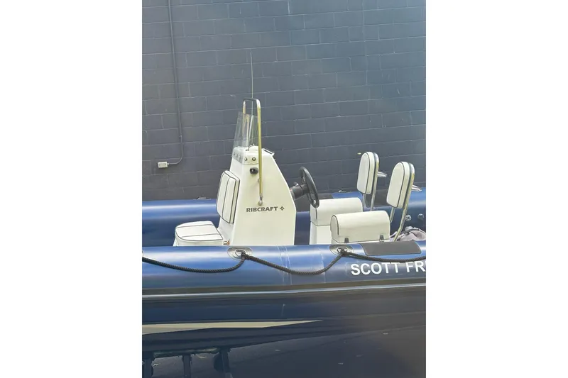 Slide: The Image of 2019 Ribcraft 7.8 boat with blue hull and white seating, docked near a wall. - 3