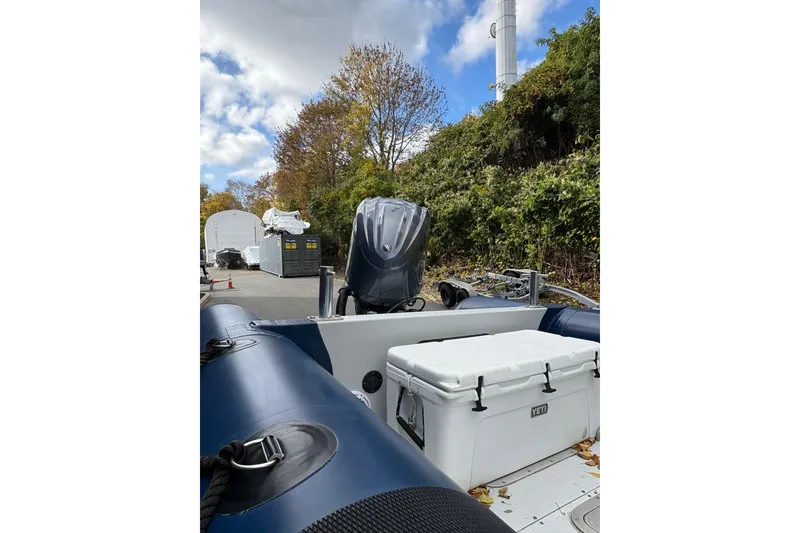 Slide: The Image of 2019 Ribcraft 7.8 boat with outboard motor and Yeti cooler, parked outdoors. - 9