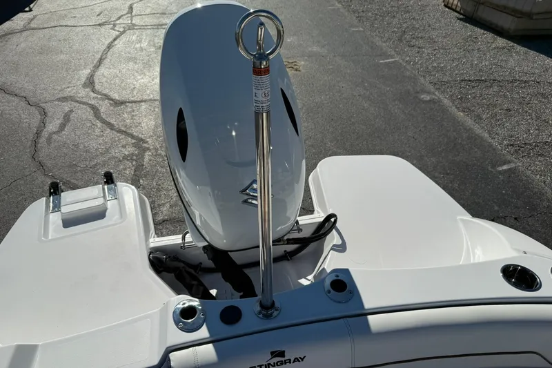 Slide: The Image of 2026 Stingray 191 DC boat stern with motor and ski tow bar on pavement. - 10