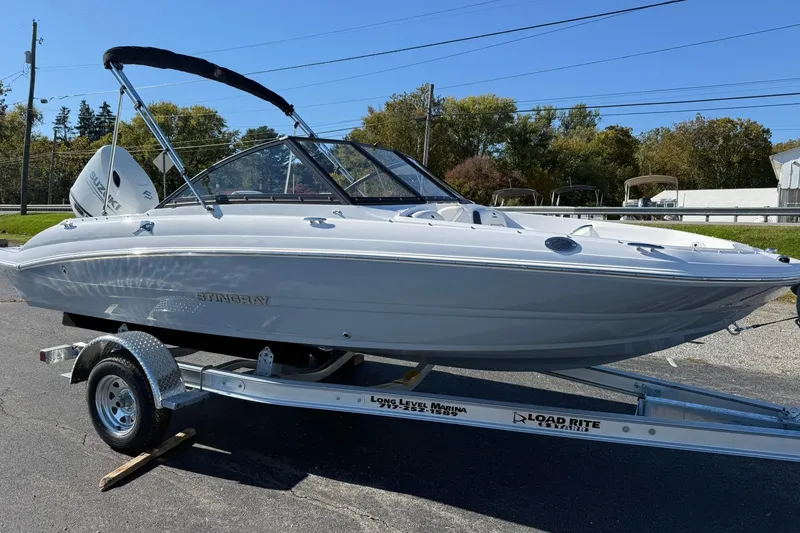 Slide: The Image of 2026 Stingray 191 DC boat on trailer, parked outdoors under clear blue sky. - 6