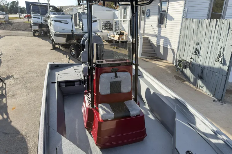 Slide: The Image of 2026 Excel Bay Pro Elite 220 boat with red console, parked near trailers. - 14